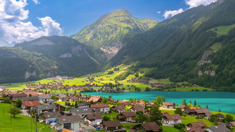 An idyllic Swiss village by a turquoise lake surrounded by green Alpine slopes