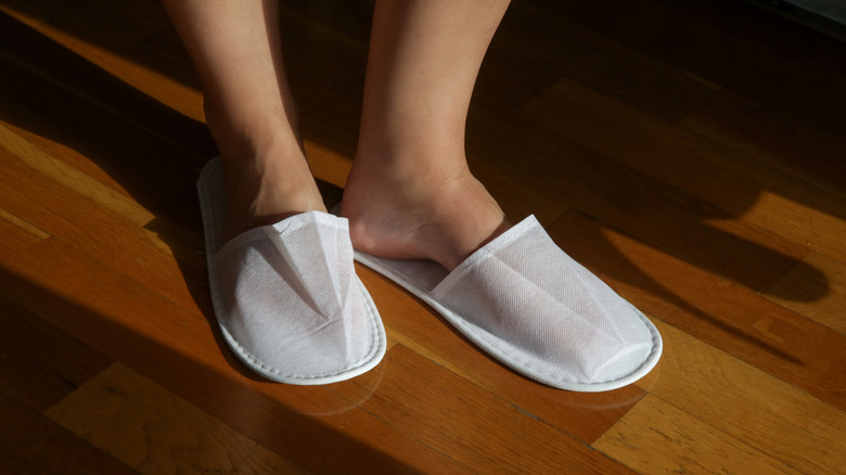 A person wearing hotel slippers.
