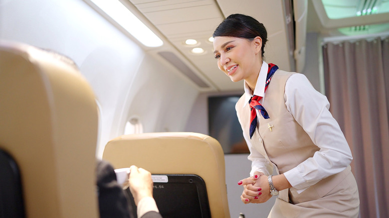 A friendly flight attendant serving passengers on a plane.