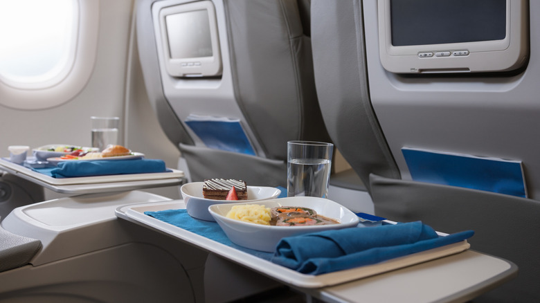A photograph of food on a tray on a plane.
