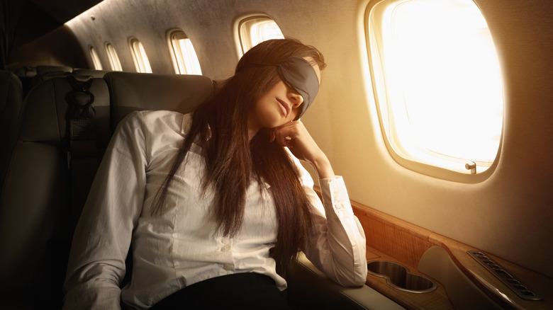A woman sleeping on a long haul flight with an eye mask.