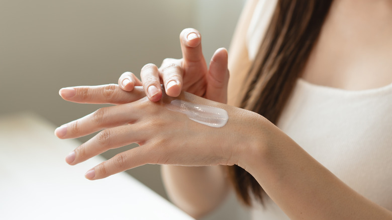 Woman rubbing lotion on her hand.