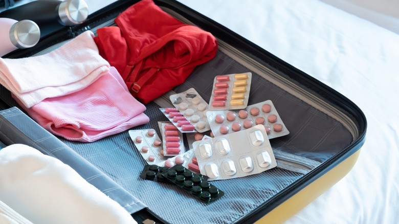 Medicine and clothes in opened suitcase