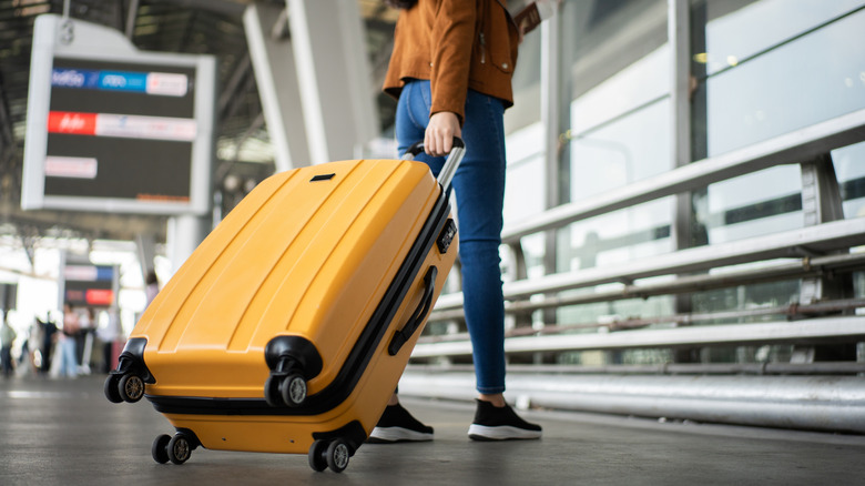 Person with a yellow suitcase at an airport