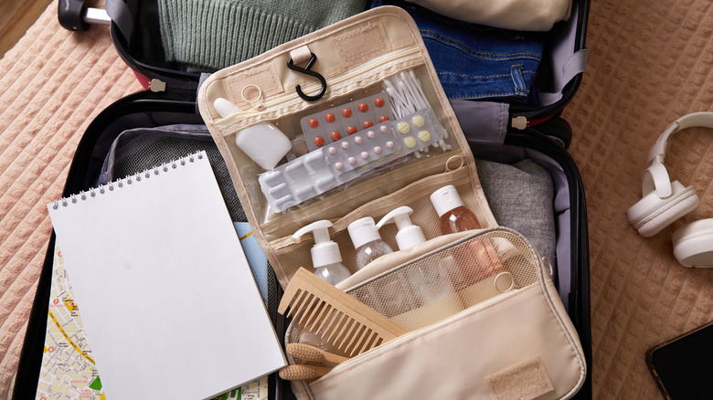 Open toiletries bag laying inside a suitcase