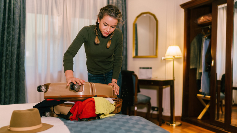 Girl with overflowing suitcase with clothes spilling out
