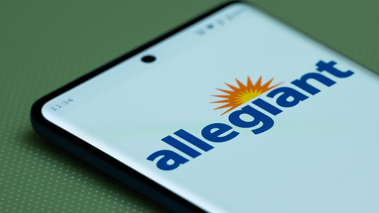 Official logo of Allegiant Air is seen on a smartphone screen sitting on a green background