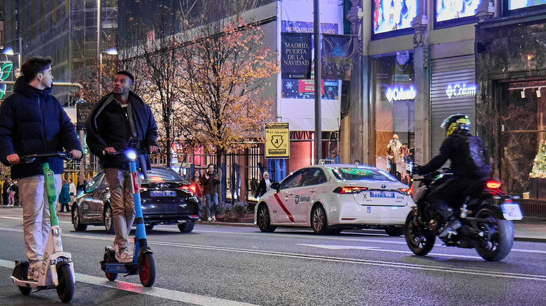 Madrid street scene with cars, a motorcycle, and men on scooters