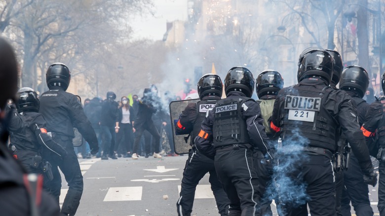 French riot police facing protesters in the smoke of tear gas in Paris, France