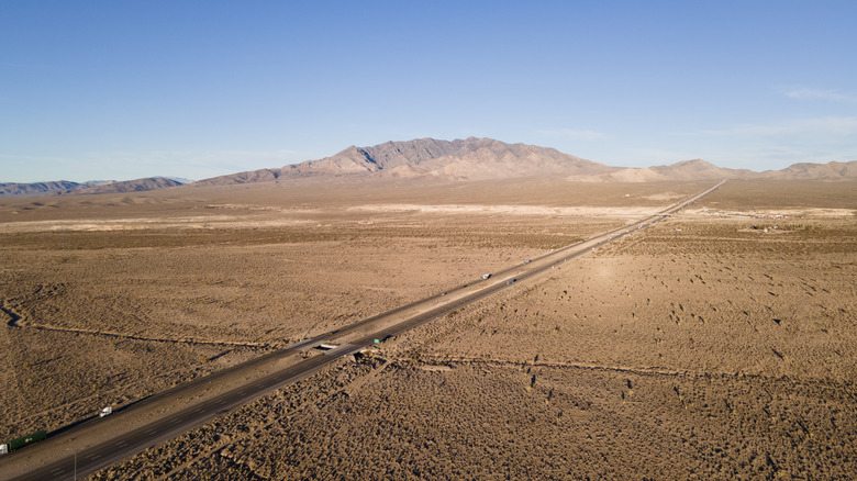 Aerial view of the I-15 highway stretching through the desert towards Las Vegas with mountains in the distance.