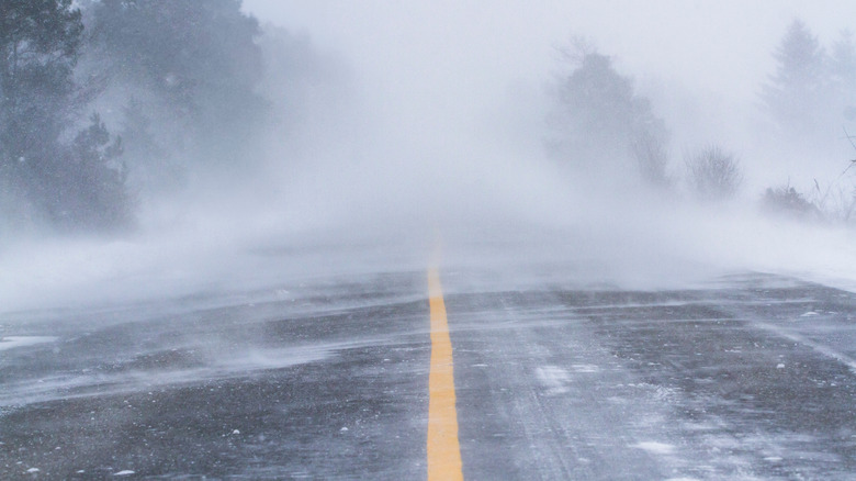 Fierce blizzard covers a strip of road with snow