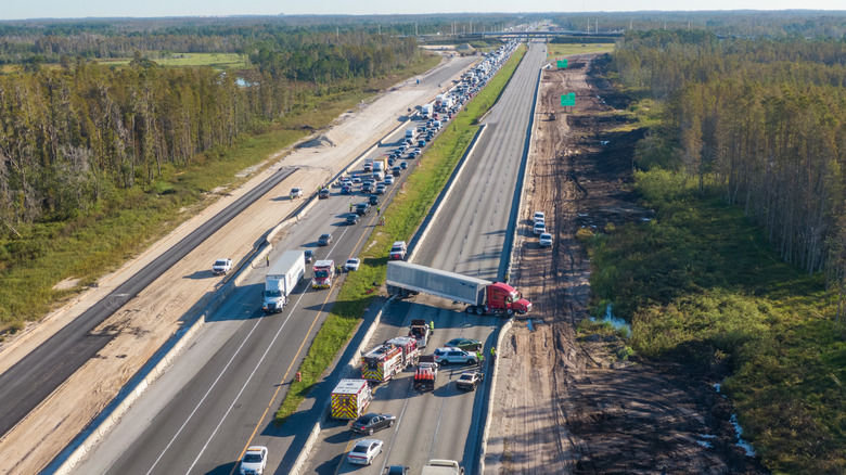 Scene of an accident on I-4 with traffic, first responders, and green trees, photographed aerially with limited sky, in Florida