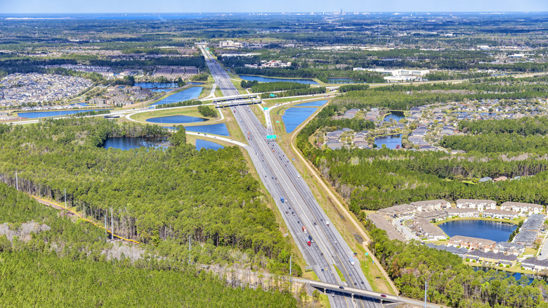 I-95 fills the screen in this aerial image showing a gray highway and dense, green trees, and blue lakes in Florida