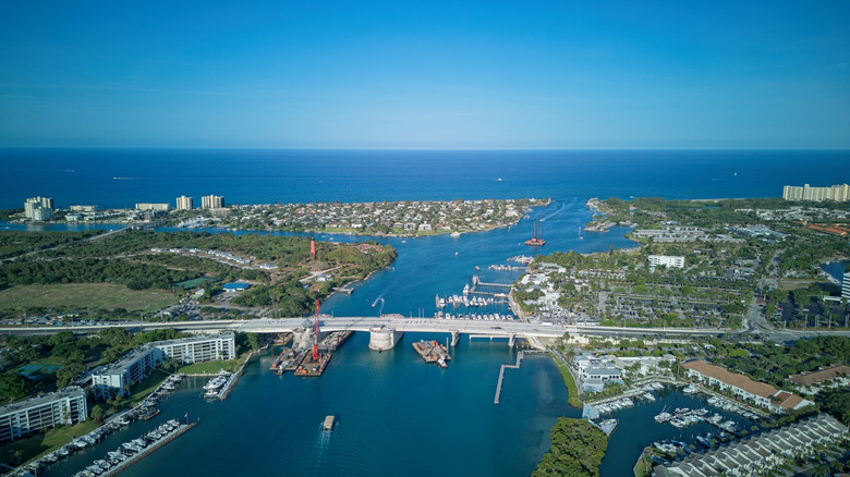 Aerial view of a bridge on U.S. 1 in Florida with an expansive cerulean ocean, green trees and fields, and a cloudless sky