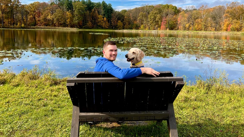 A man sits on a bench with a goldendoodle at Cuyahoga Valley National Park
