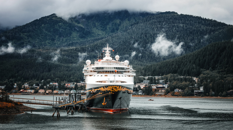 Disney Cruise Line ship in port in Alaska with mountains and a village in the backround