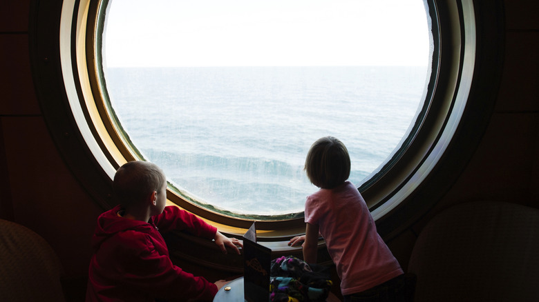 Children looking out of a signature large porthole on a Disney Cruise Line ship
