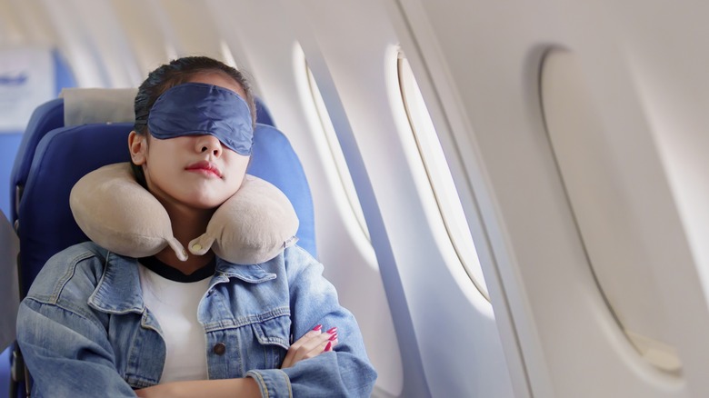 Airplane passenger wearing an eye mask and neck pillow