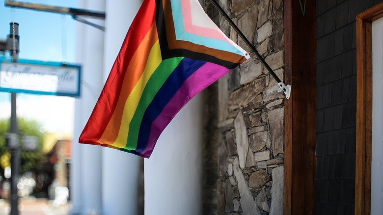 A Pride flag flying outside of a shop downtown
