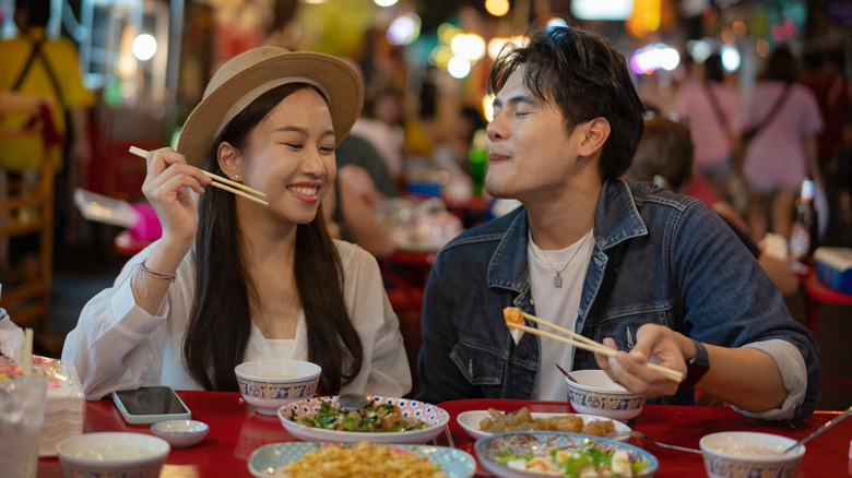 A couple eating street food at a market in Bangkok