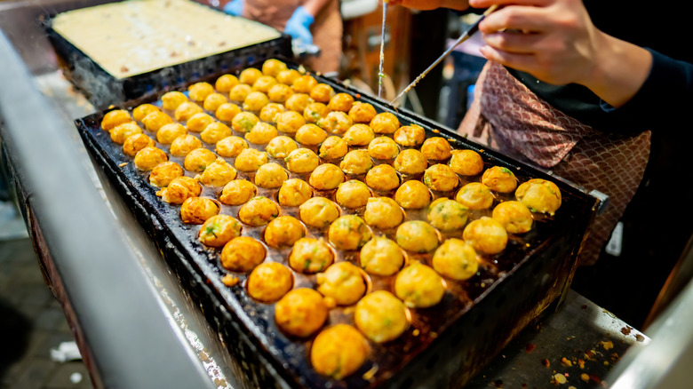 a street vendor cooking takoyaki in Dotonbori in Osaka