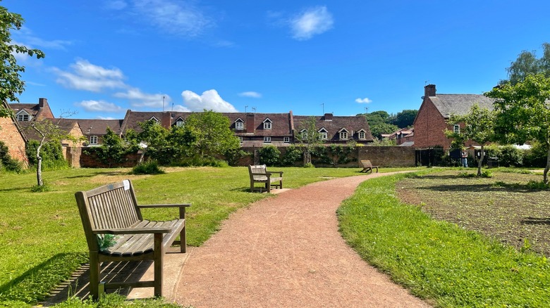 A wooden bench on a dirt path at the Queen Elizabeth II Jubilee Gardens, Bedley, UK