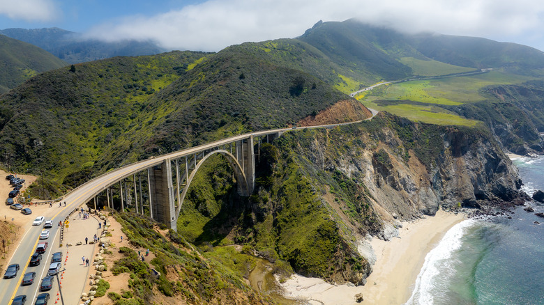 A bridge crosses a valley by green oceanside cliffs