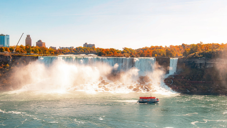Water crashing over the Niagara Falls with autumn colors in the forests behind