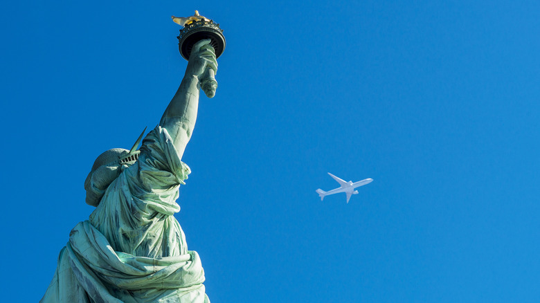 An airplane flying over the Statue of Liberty