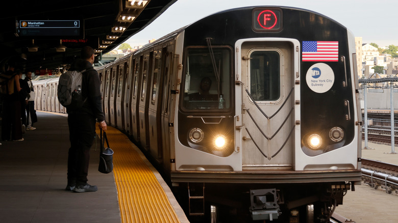 People wait to get on an F train in New York City