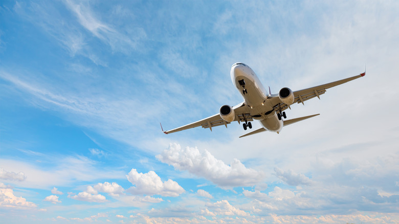 Airplane taking off with blue sky and light clouds in background