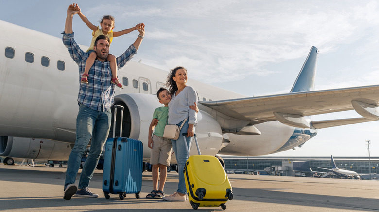 Smiling family in front of an airplane