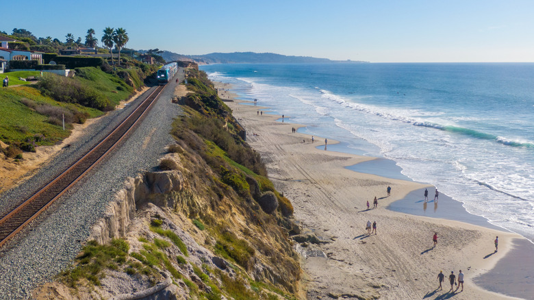 Daytime Drone Images of the Coaster and Amtrak Trains Hugging The Cliffs Along The Beach in Sunny Del Mar, California: Travel, Transportation, Outdoors