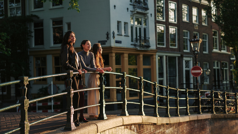 Three women on edge of Amsterdam's canals