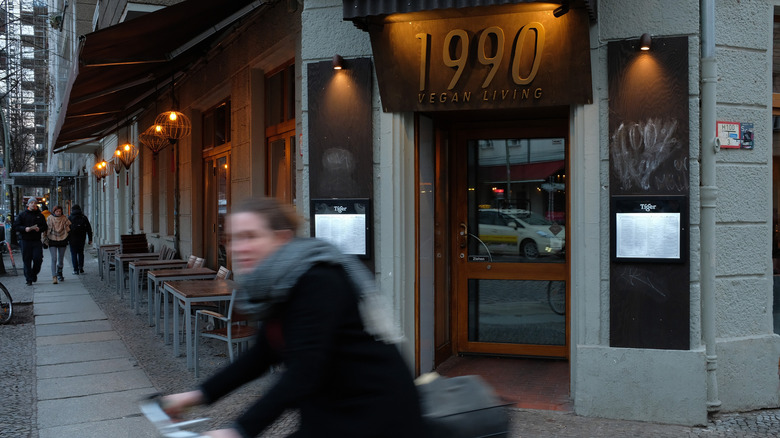 A young woman bikes past 1990 Vegan Living, a restaurant that offers Vietnamese-inspired vegan dishes in Friedrichshain district of Berlin