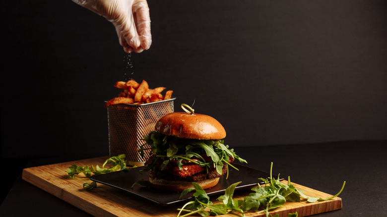 vegan burger with plant based patty and arugula on wooden board. g.