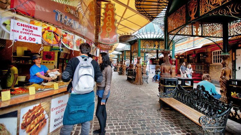 Customers wandering around the street food stalls of Camden market.