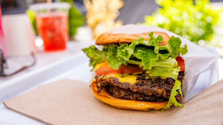 A ready to eat vegan cheeseburger on an outdoor cafe table in New York City on a sunny day.