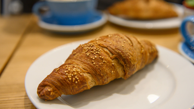 Close up photograph of a fresh baked vegan croissant set on a plate for breakfast at a cafe bakery in Paris, France.