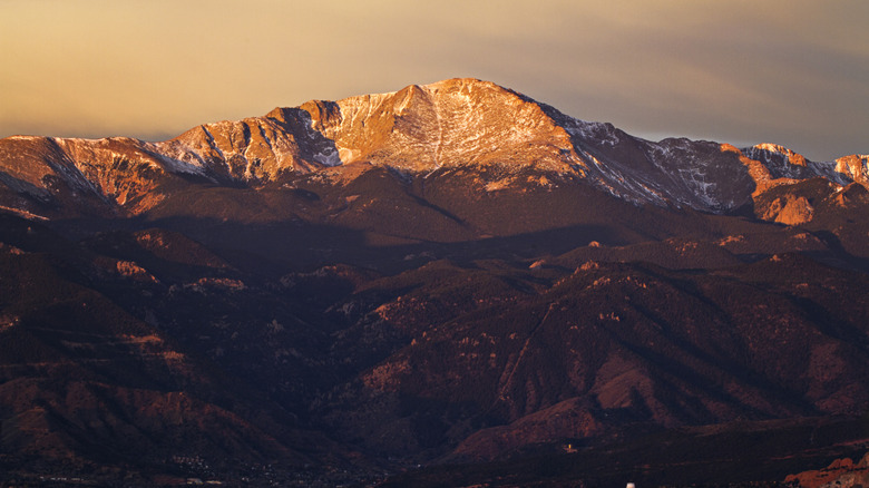 Pike's Peak summit at sunrise with a dusting of snow on top and the base in darkness