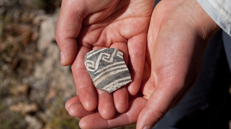 Cupped hands holding pottery shards found below Little Elden Mountain, Arizona, USA.