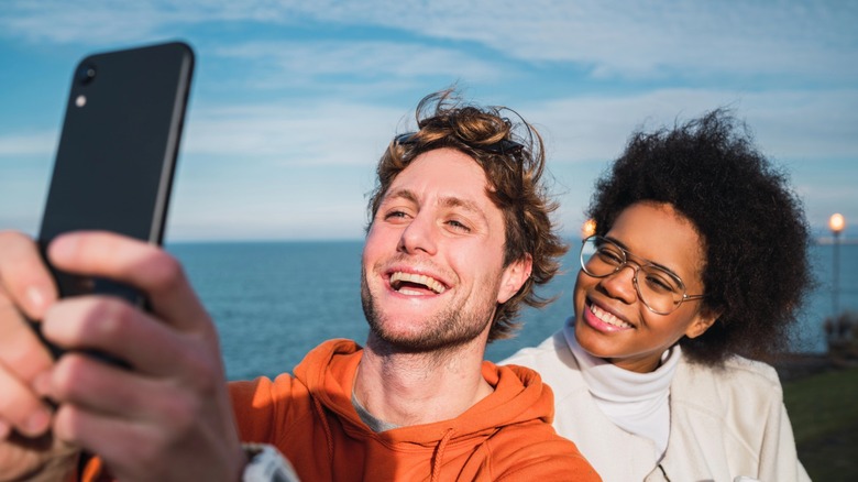 A man and woman smiling at a phone