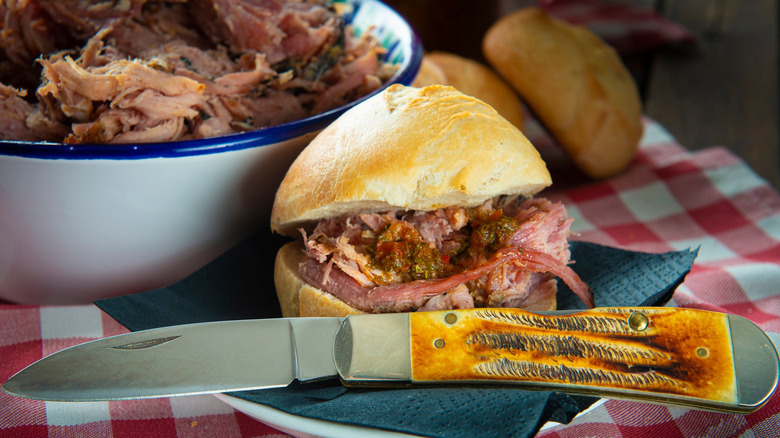 A pulled pork sandwich with a knife