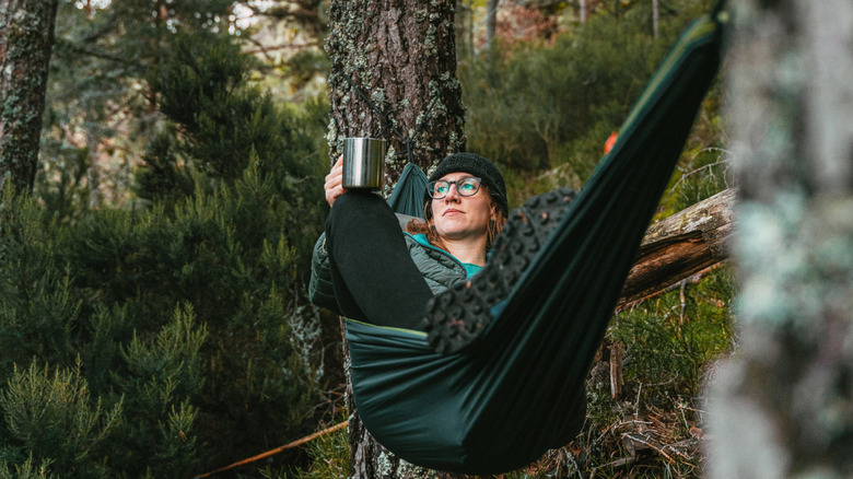 A camper in the woods in a hammock
