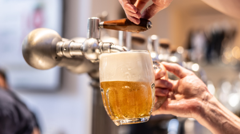 Someone pouring a beer in a beer mug from a beer tap