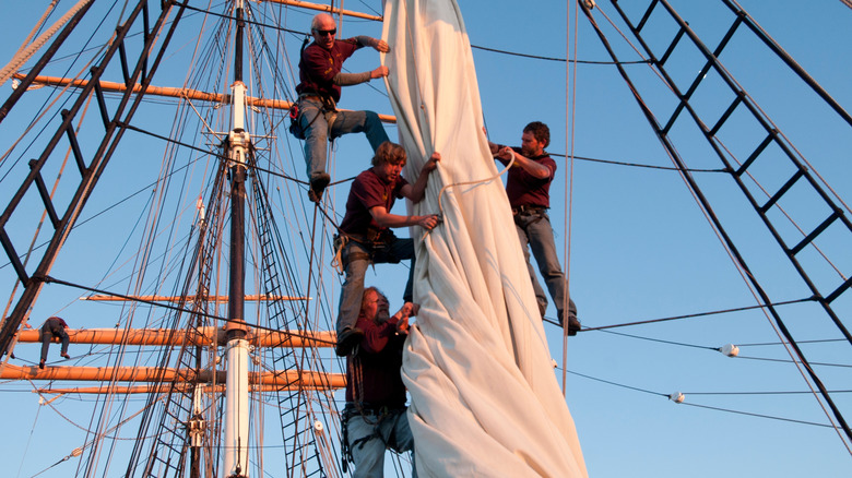 Four sailors hoisting sails on the Star of India in San Diego