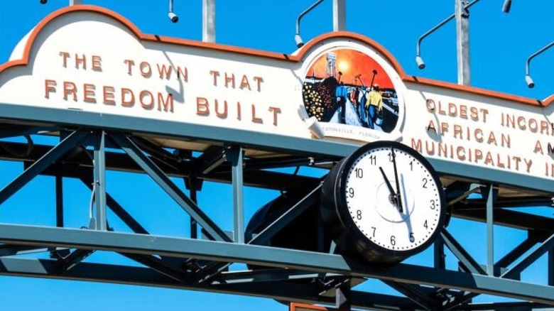 The sign in Eatonville, Florida, with a clock, against a blue sky