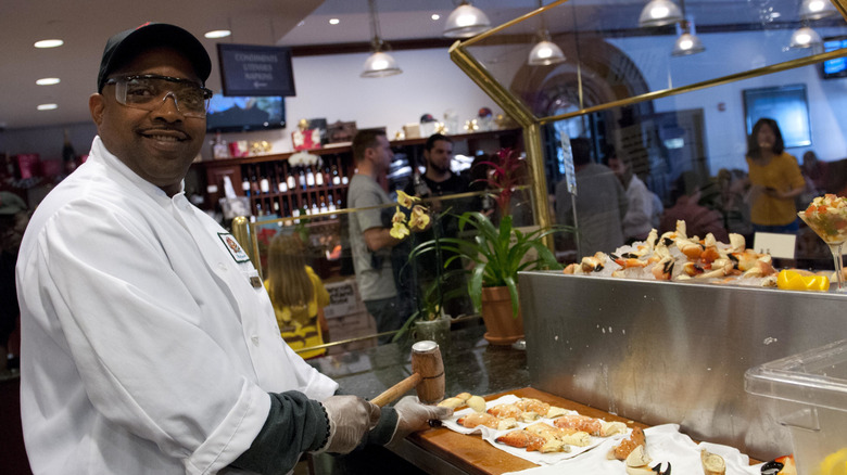 A chef at Joe's Stone Crab prepares stone crab claws for diners with a mallet and wearing googles