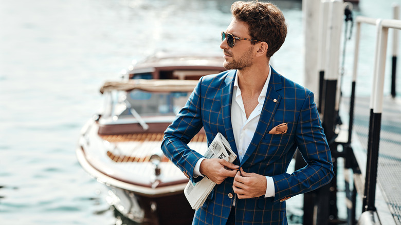 Young man dressed in suit with boat in background