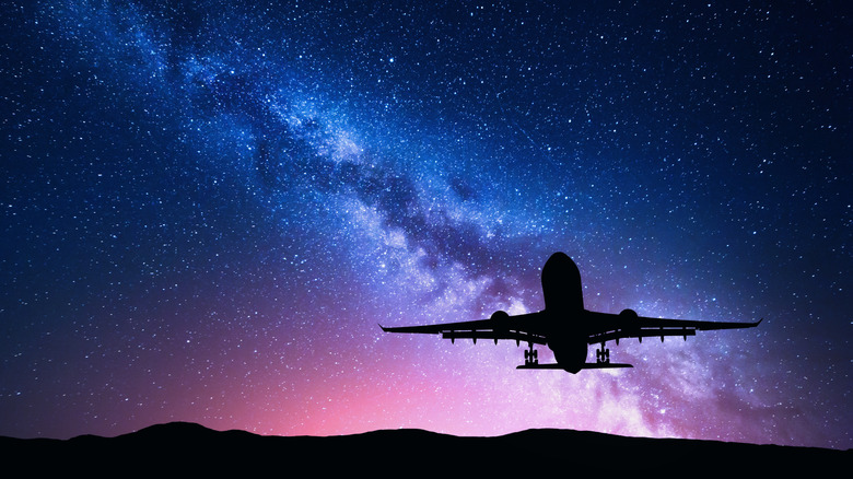 A silhouette of a plane against the night sky